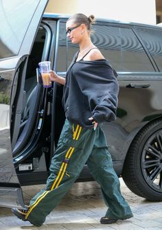 a woman in green pants stepping out of a vehicle