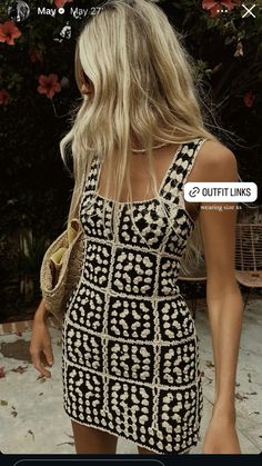 a woman with blonde hair wearing a black and white patterned dress looking at her cell phone