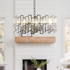 a chandelier hanging over a fireplace in a room with white walls and furniture