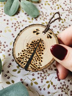 a woman's hand holding a wooden ornament