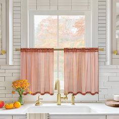 a kitchen with white cabinets and orange flowers in the window sill, along with a gold faucet