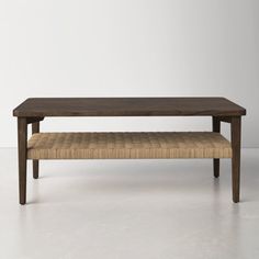 a coffee table with a bench underneath it on a white floor in front of a wall