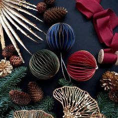 christmas decorations and pine cones on a black surface with red satin ribbon around the edges