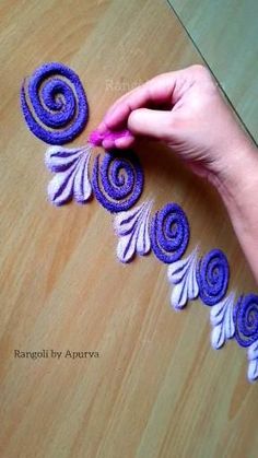 someone is making something out of yarn on the wooden table and it looks like swirls