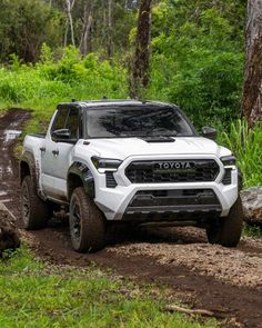 a white toyota pickup truck driving down a muddy road