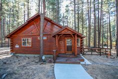 a log cabin sits in the woods near a picnic table