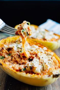 a fork is lifting up some food out of an open stuffed bell peppers shell on a wooden table