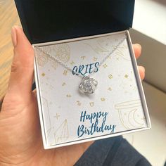 a person holding up a birthday card with a heart shaped pendant in it's box