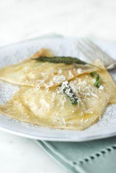 a white plate topped with ravioli covered in cheese