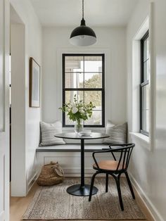 a dining room with a window seat, table and chair next to a rug on the floor