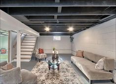 a living room with couches, chairs and a coffee table in front of a stair case