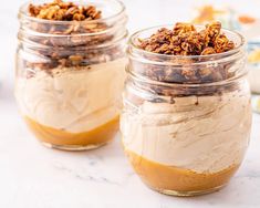 two jars filled with desserts sitting on top of a white marble countertop next to each other