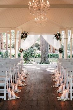 an outdoor wedding venue with white chairs and chandelier