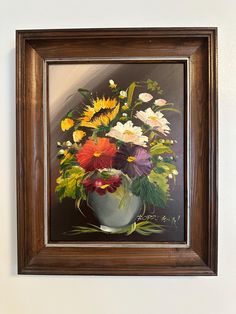 an oil painting of flowers in a vase on a white wall by a brown frame