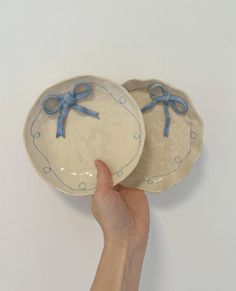 two plates with blue bows on them being held by a hand