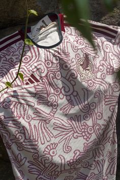 a white and red shirt is hanging on a clothes line next to a tree branch