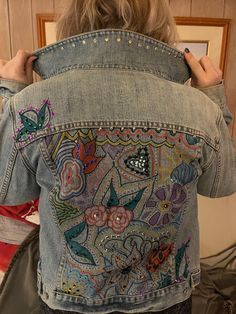 the back of a woman's jean jacket with embroidered flowers and butterflies on it