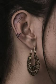 a close up of a person's ear with tattoos on it and an ear piercing