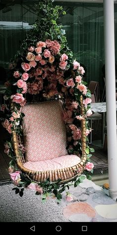 a wicker chair with pink flowers and greenery on the back is sitting in front of a building