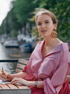 a woman in a pink dress sitting on a bench