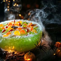 a green halloween dessert with orange and yellow candies on it, surrounded by spider webs