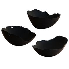 three black bowls with holes in them on a white background