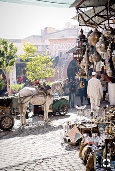 a horse pulling a cart in front of a market with lots of items on display