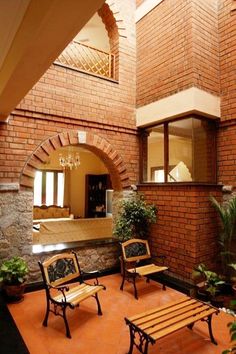 two wooden benches sitting next to each other in front of a brick building with arched windows