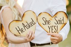 two people holding wooden signs that say he asked she said yes