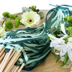 some flowers are sitting in a glass vase on a plate with chopsticks next to it