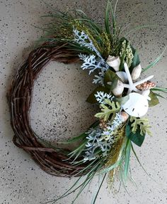 a wreath made out of branches and white flowers on top of a cement floor with snowflakes