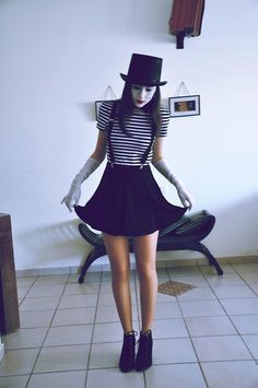 a woman in a black and white striped top hat and dress with tights on