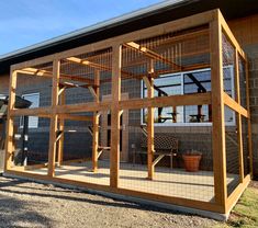 a large wooden structure sitting on top of a gravel field next to a building with windows