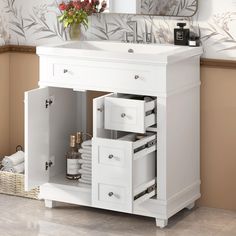 a white bathroom vanity with drawers under a mirror and flowers on the sink counter top