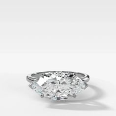 an oval diamond ring with three pear shaped diamonds in the center, on a white background