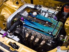 the engine compartment of a yellow car with its hood up and it's front end exposed