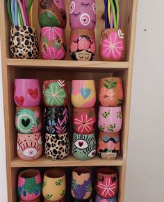 a wooden shelf filled with lots of colorful painted pots and vases on top of each other