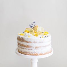 a white cake with lemons and lavender sprinkles on top is sitting on a pedestal