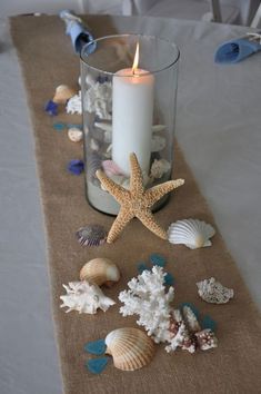 there is a candle on the table with sea shells and starfishs around it