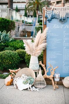 a sign with feathers and other items on the ground next to some plants in front of it