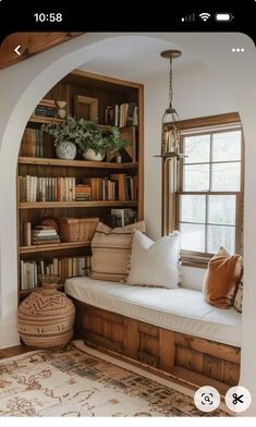 a window seat with bookshelves and pillows in the corner, next to a rug