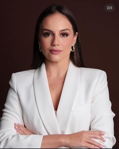 a woman in a white suit with her arms crossed