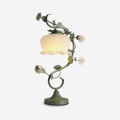 a table lamp with flowers on it and a glass shade over the light, against a white background