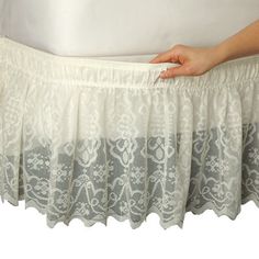 a person is holding the bottom of a white bed skirt with lace on it,