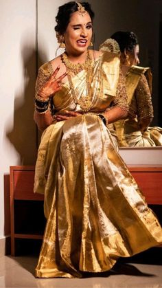 a woman sitting on top of a wooden table in a gold dress and headpiece