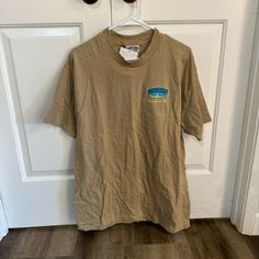 Ron Jon Surf Shop Tan Graphic Shirt Size L In Good Used Condition Brand New With Tags Casual Beige Graphic Print Shirt, Casual Beige Shirt With Graphic Print, Casual Khaki Tops For Beach, Beige Crew Neck Top For Beach, Summer Graphic Tee Shirt In Brown, Khaki Graphic Print Short Sleeve Tops, Brown Summer Graphic Tee Shirt, Summer Khaki Crew Neck Shirt, Summer Brown Graphic Tee Shirt