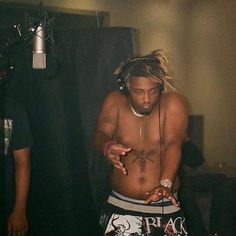 a shirtless man with headphones on standing in front of a microphone and recording equipment