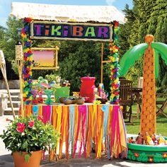 a tiki bar decorated with colorful streamers and decorations for a tropical themed party