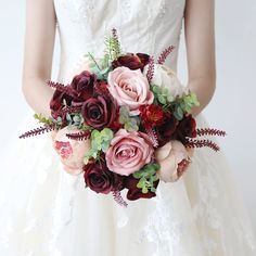 a bridal holding a bouquet of pink and red flowers on her wedding day in front of a white background