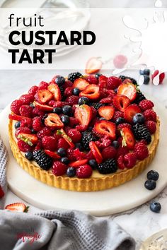 a fruit custard tart on a plate with berries and blueberries in the middle